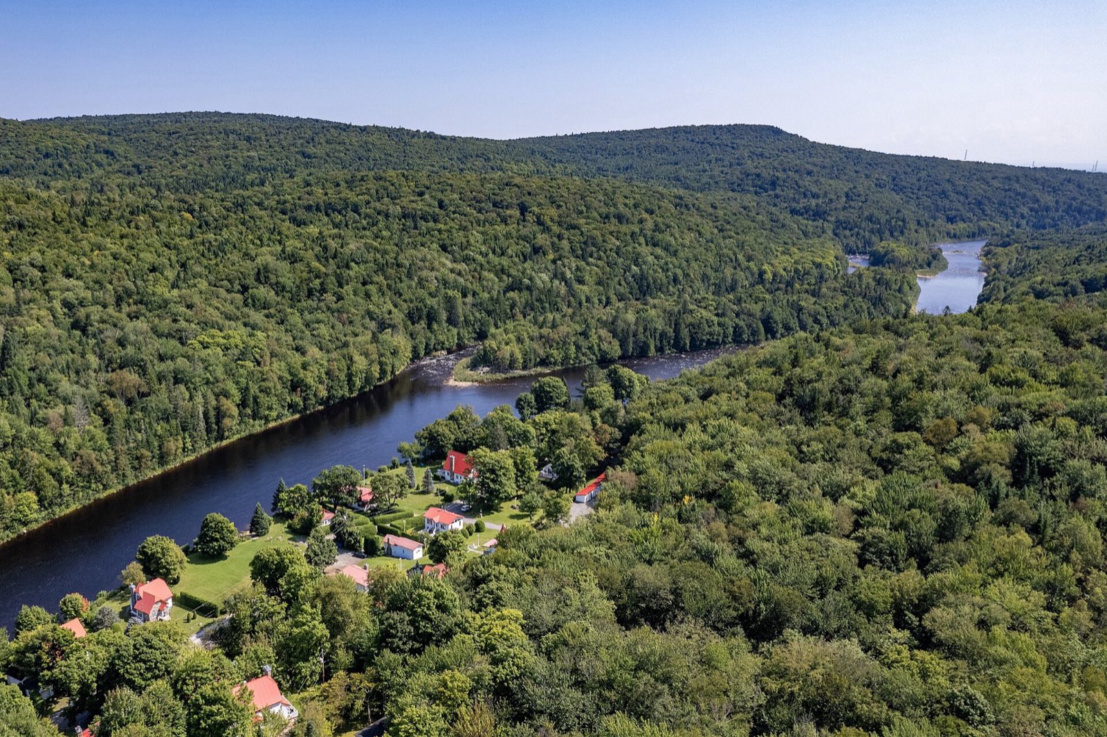Vallée boisée et résidences en bordure de rivière
